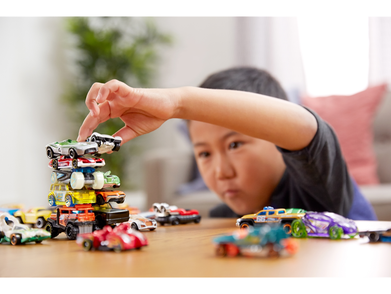 Un enfant joue avec une pile de voitures Hot Wheels.