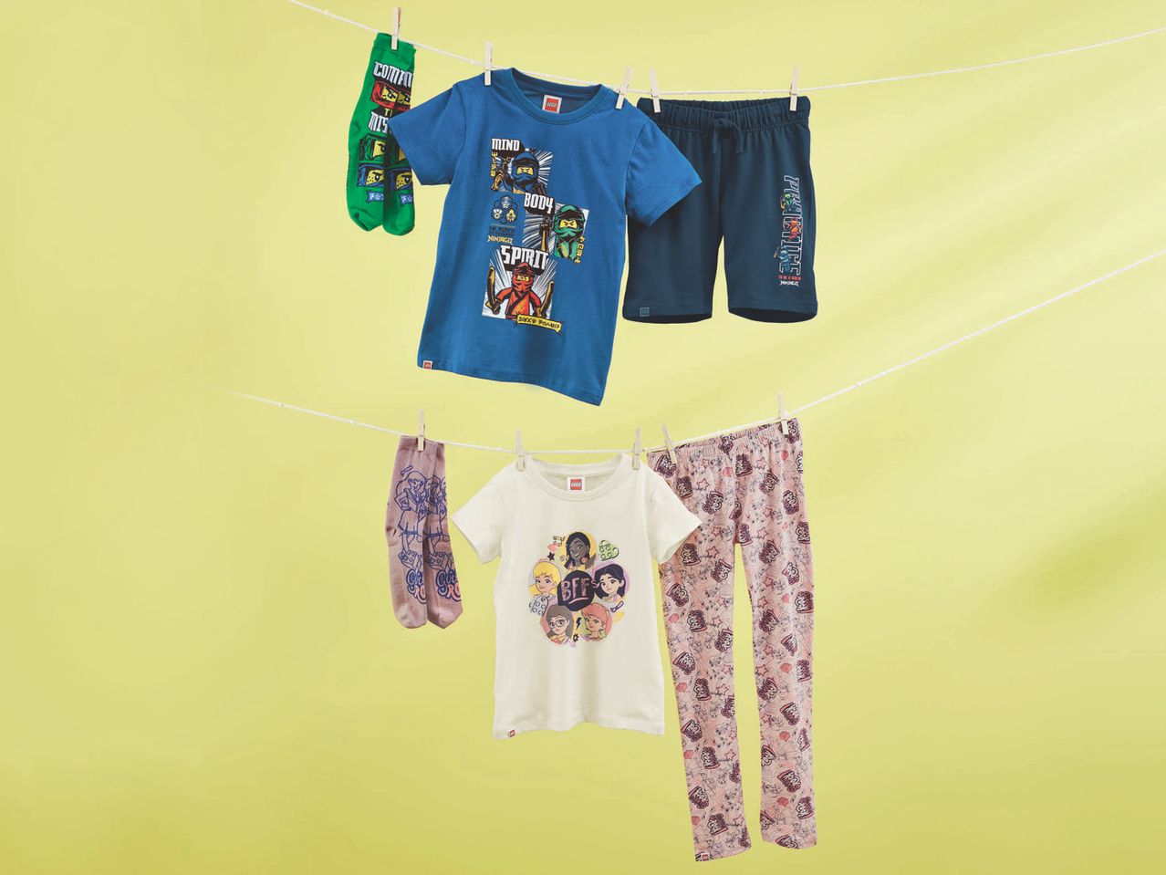 Abbigliamento per bambini a tema LEGO Ninjago e Friends appeso su uno stendibiancheria.