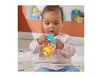 A baby playing with a colorful animal-shaped rattle toy while sitting on a patterned rug.