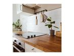 Modern kitchen with a wooden countertop, induction hob, and white subway tile backsplash.