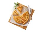A spiral cheese pie, cut into slices, sits on a wooden board with a knife and parsley.