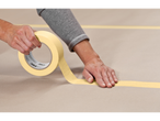 A person applying 3M masking tape to a surface.