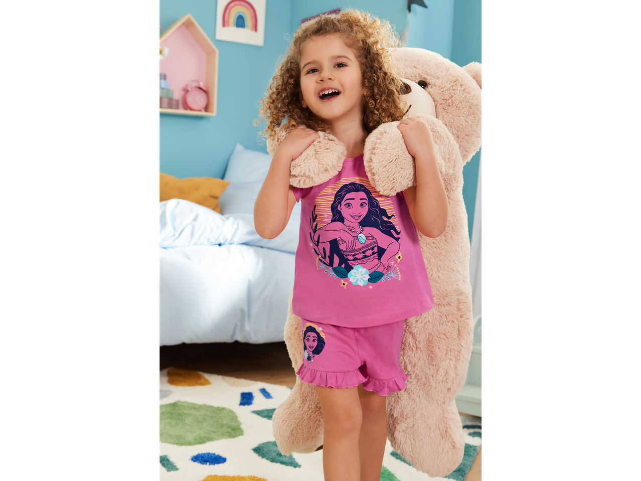 Child in Moana pajamas with a plush toy.