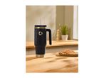 Black and gold travel mug with a straw on a wooden counter next to waffles.