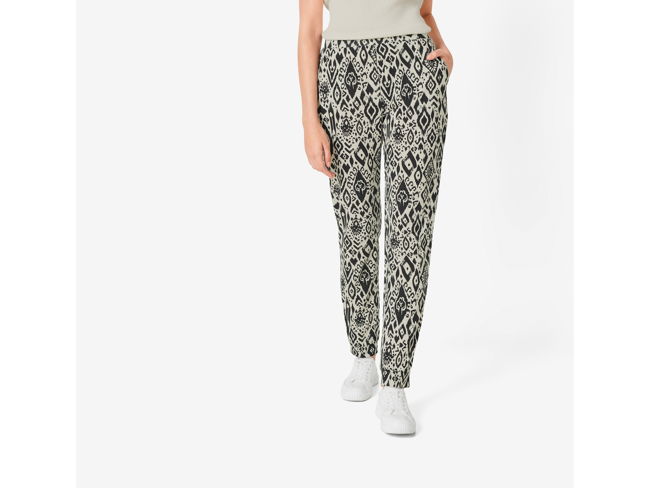 Femeie purtând pantaloni cu model și adidași albi.