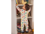 Baby in alphabet pajamas reaching for a book, wearing Lupilu® baby shoes.