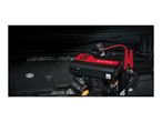 A portable car battery jump starter with compressor connected to a car battery under the hood.