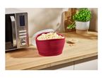 A SilverCrest microwave next to a red bowl of popcorn on a wooden counter.