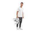 Man in white t-shirt and grey sweatpants holding a Crivit mini bike trainer.