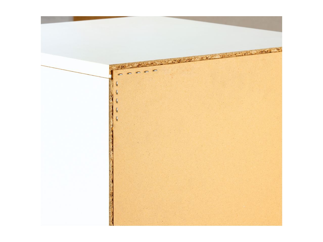 Close-up of a particle board shelf with staples, showing construction details.