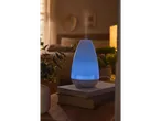 Difuzor de aromă cu ultrasunete LIVARNO home cu lumină albastră pe cărți lângă pat.