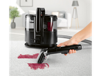 Aspirador de carpetes Cleanmaxx removendo uma mancha vermelha de um tapete branco.