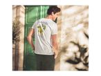 Man in white t-shirt with lemon print and 'La Dolce Vita' text, dark green trousers.