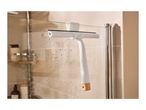White shower squeegee with a wooden handle hanging on a wet glass shower door.
