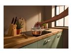 A person lifting the lid of a copper saucepan on an induction hob in a kitchen.