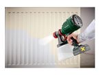 A person spray painting a radiator white with a cordless paint spray gun.