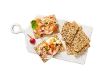 Crackers met gerookte zalm, roomkaas en groenten op een witte snijplank.