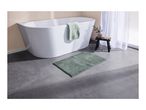 A white bathtub with a green bath mat and a small stool in a bathroom.