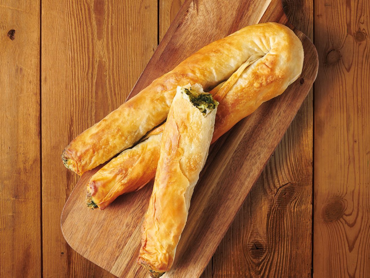 Баници със сирене и спанак на дървена дъска.