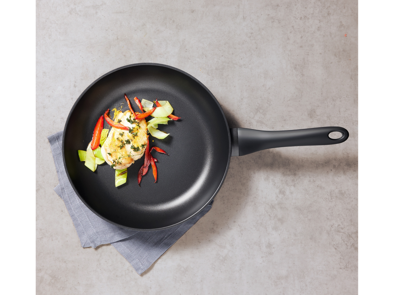 Padella nera con pollo e verdure arrostite.
