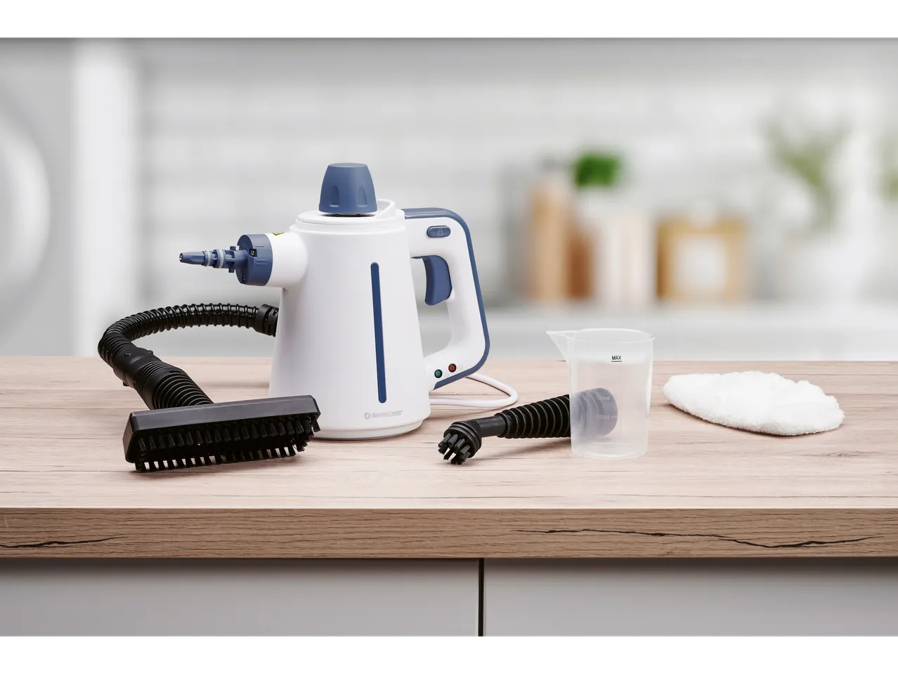 Ръчна парна чистачка Silvercrest® с аксесоари върху дървен плот.