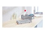 Grey foldable crates on a wooden countertop with toiletries and towels, next to a sink.