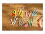 Colorful plastic cutlery sets in yellow, pink, blue, white, and green, with party decorations on a wooden table.