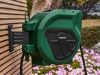 A green Gardena wall-mounted hose reel with a black central mechanism.