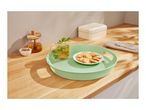 A light green serving tray with mint tea and cookies on a wooden countertop.
