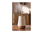 An elegant essential oil diffuser emitting mist on a wooden table.