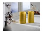 Two golden LED candles on a white windowsill with a blurred winter scene outside.