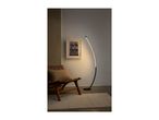 A modern curved floor lamp illuminates a room with a leather chair and framed art.