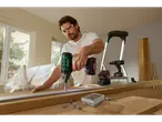 Um homem usa uma furadeira sem fio Parkside para construir móveis.