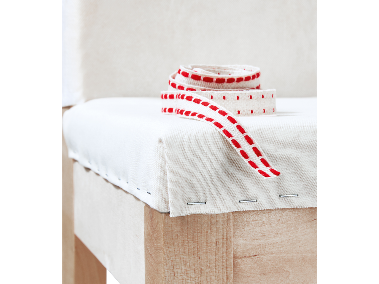 Agrafador elétrico PARKSIDE fixando tecido branco com fita vermelha numa base de madeira.