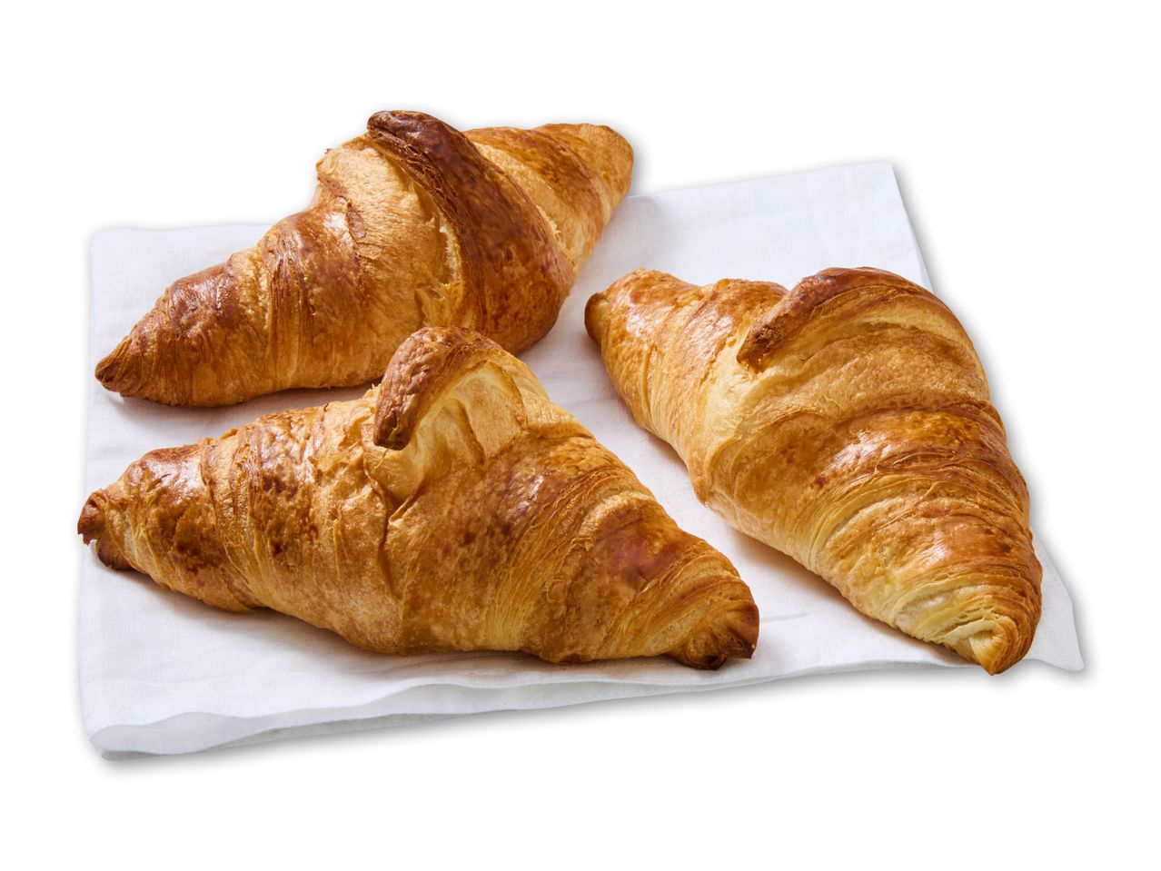 Tre gyldenbrune croissanter på en hvid serviet, klar til morgenmad.