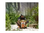 A fairy garden house with a 'WELCOME' sign, surrounded by greenery and white pebbles.