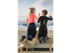Two kids in CRIVIT base layers and ski pants looking out a window at snowy mountains.
