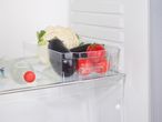 A clear plastic Fridge Organiser, in a refrigerator holds cauliflower, eggplant, and tomatoes.