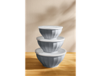Three gray mixing bowls with white lids, stacked on a wooden table.