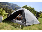 Homem com saco de dormir CRIVIT dentro de uma tenda de campismo, com montanhas ao fundo.