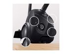 Black vacuum cleaner with power control dial and textured surfaces on a wooden floor.