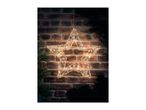 Illuminated star decoration hanging against a brick wall with pine branches