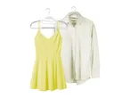 A yellow sundress and an off-white long-sleeve shirt hang on clothes hangers.