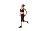 Woman running in a black sports bra and patterned capri leggings.
