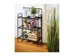 Black metal plant stand with various potted plants, a watering can, and a wooden storage box.