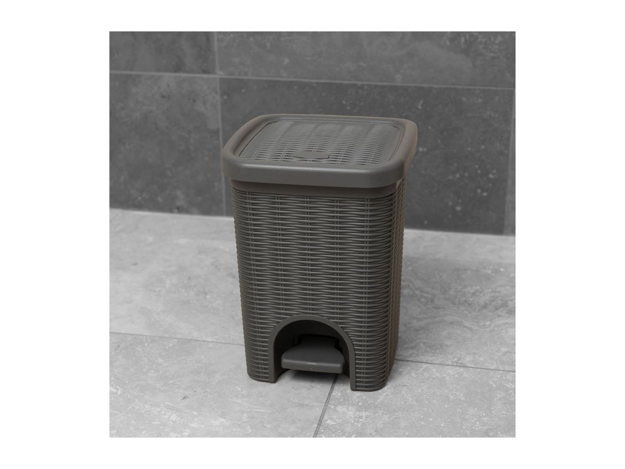 Grey rattan-style pedal bin with a textured lid on a tiled floor.