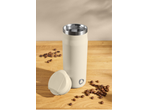 Termos de cafea bej cu boabe de cafea pe o masă de lemn.