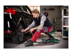 Woman using a creeper seat to change a car tire with a lug wrench in a garage.