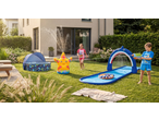Kids playing with a shark water slide, starfish sprinkler, and paddling pool in a garden.