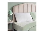 A bed with a beige headboard, white pillow, and light green bedding, next to a mint green lamp.